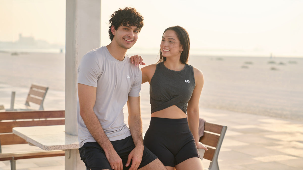 Man and woman relaxing at a beachside cafe in Urthlete activewear