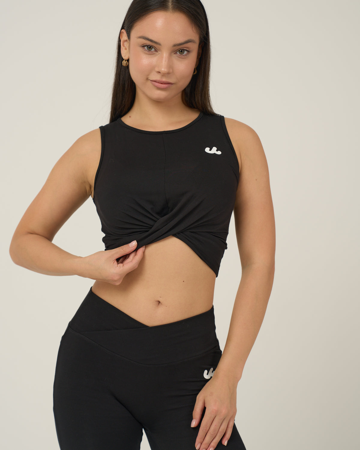 Woman in the Urthlete bamboo fitted tank in coal black with a twist front hem
